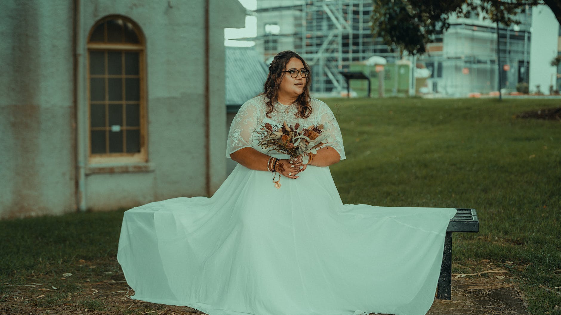 bride in wedding dress sitting on bench